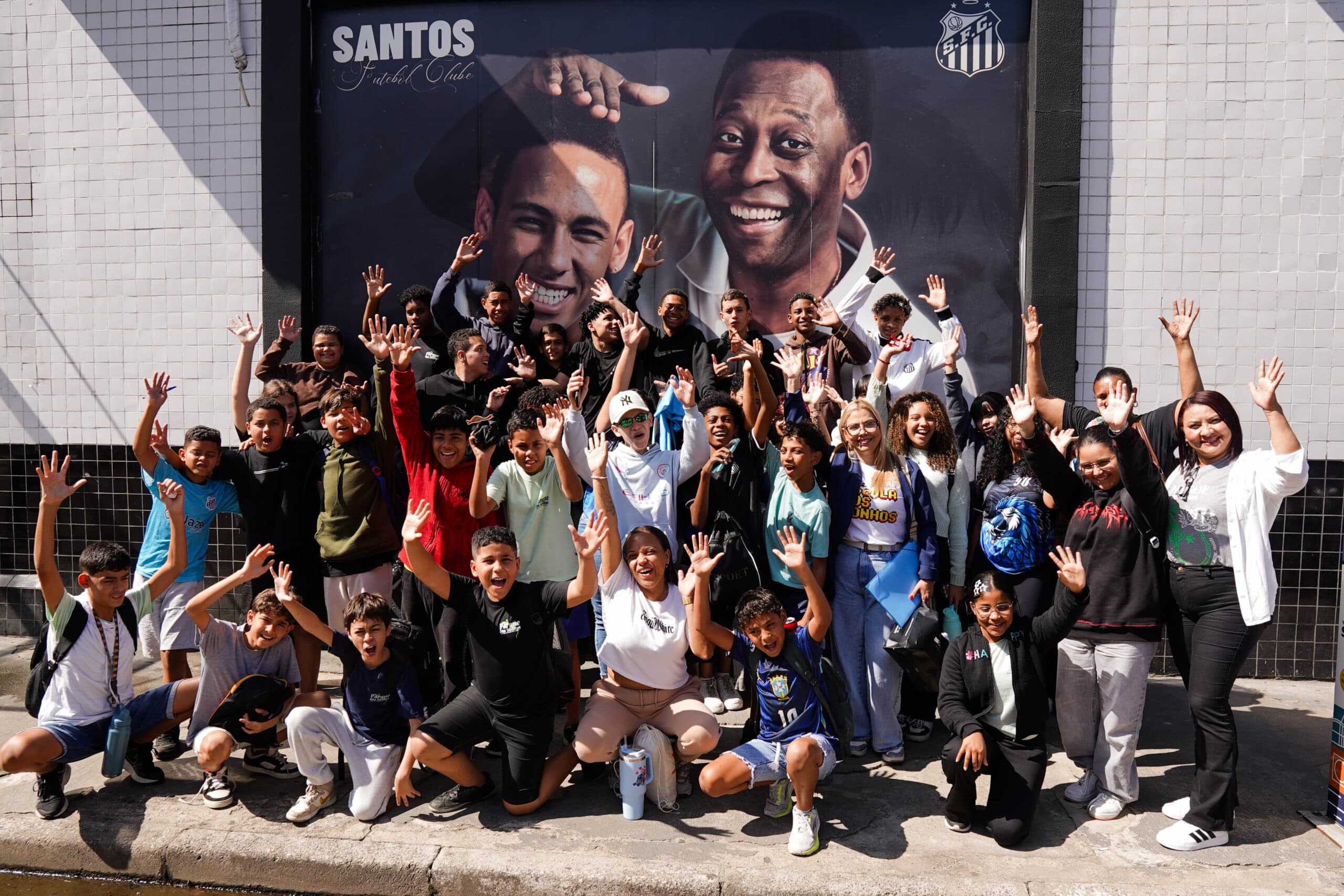 Visita dos alunos da Escola Estadual Parque dos Sonhos à Vila Belmiro com foto histórica de Placar ao fundo - Divulgação/Seduc